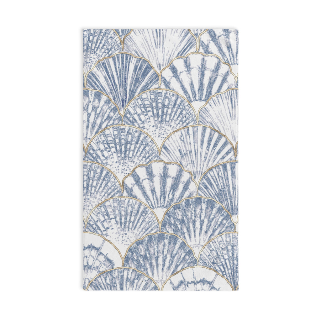 Towel with shell pattern hanging on a towel rack in a bathroom.