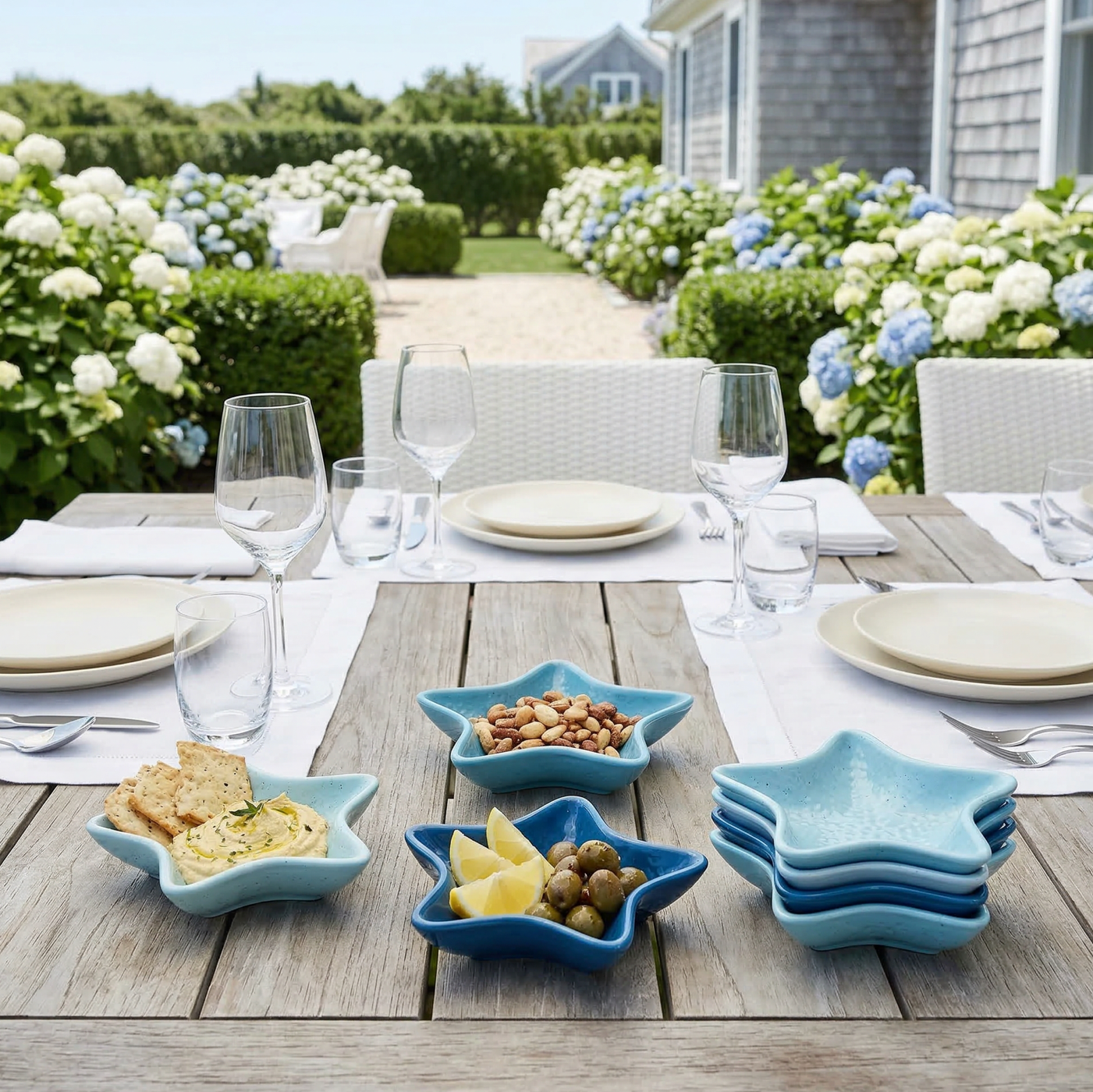 Set of four starfish-shaped blue appetizer dishes on a wooden outdoor table, filled with nuts, olives, and lemon wedges.